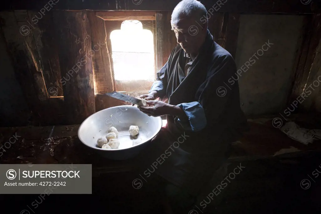 A man preparing potatos in the manufacture of arra in Ura in the Bumthang, Valley of Bhutan