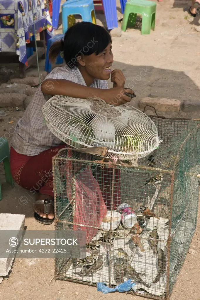 Burma, Myanmar, Yangon. A woman selling caged birds which are released into the wild on the instructions of fortune tellers to bring people__ !s wishes true.""