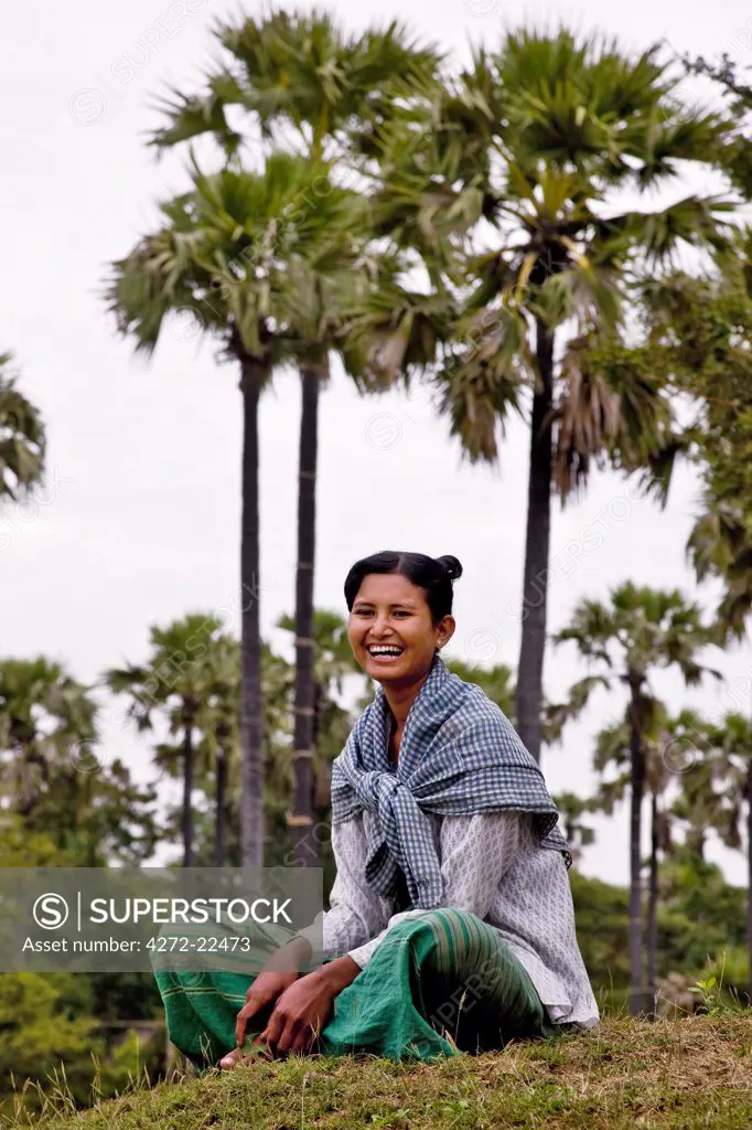 Myanmar. Burma. Bagan. A pretty girl relaxes under palm trees near Taungzin..