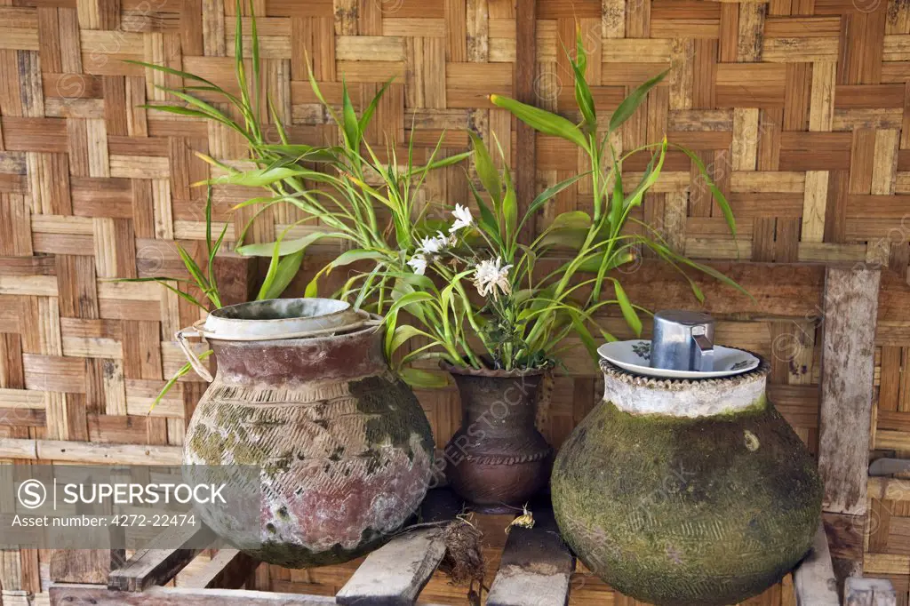 Myanmar. Burma. Bagan. Clay water pots and a vase of flowers on the verandah of a house in Taungzin.