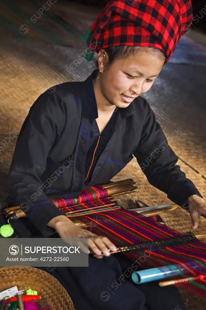 Myanmar, Burma, Lake Inle. A pretty Pa-O woman weaves brightly coloured material at Kya-Toon village.