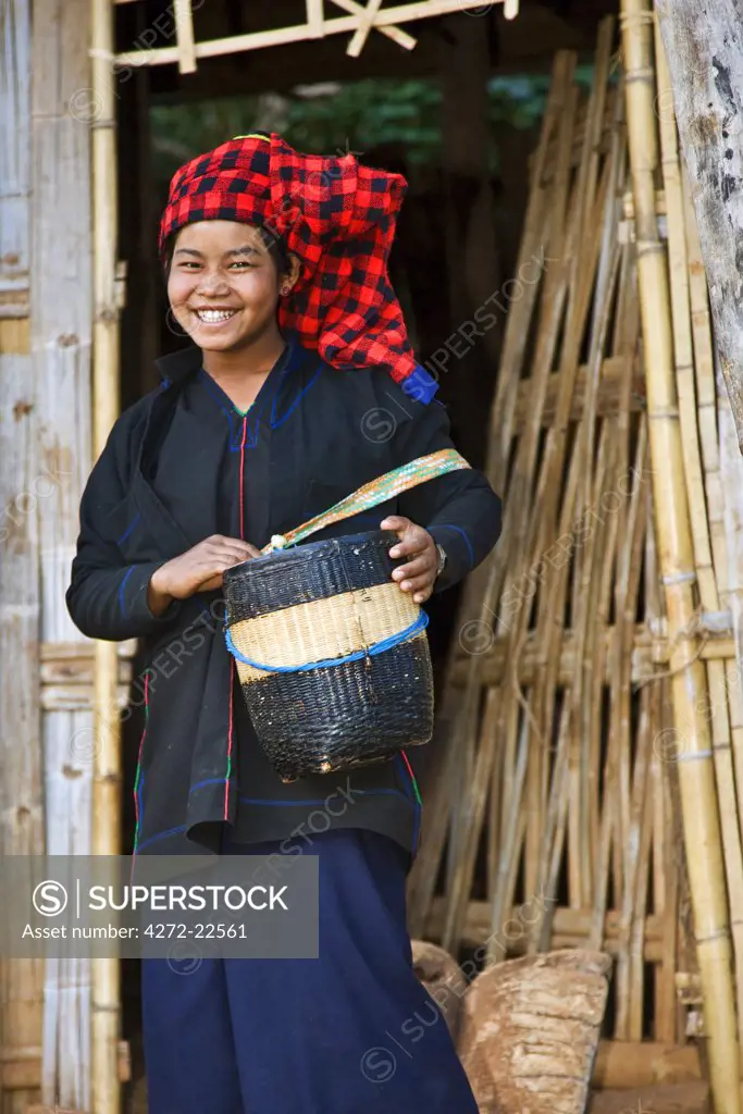 Myanmar, Burma, Lake Inle. A happy Pa-O woman leaves her house at Kya-Toon village carrying a woven bamboo basket.