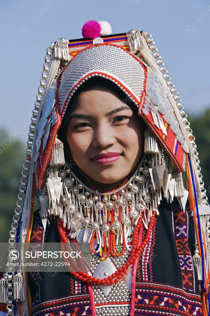 Myanmar, Burma, Kengtung. An Akha woman wearing traditional costume with a headdress of silver and beads.