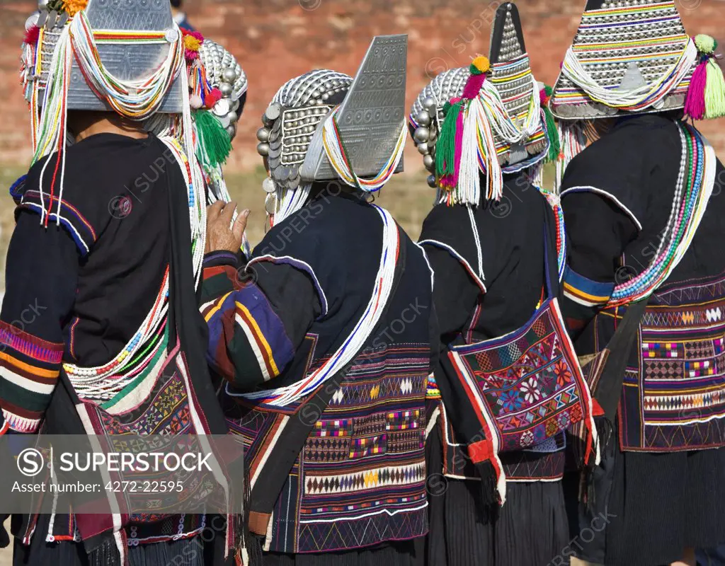 Myanmar, Burma, Kengtung. Akha women wearing embroidered jackets and traditional headdresses of silver and beads.