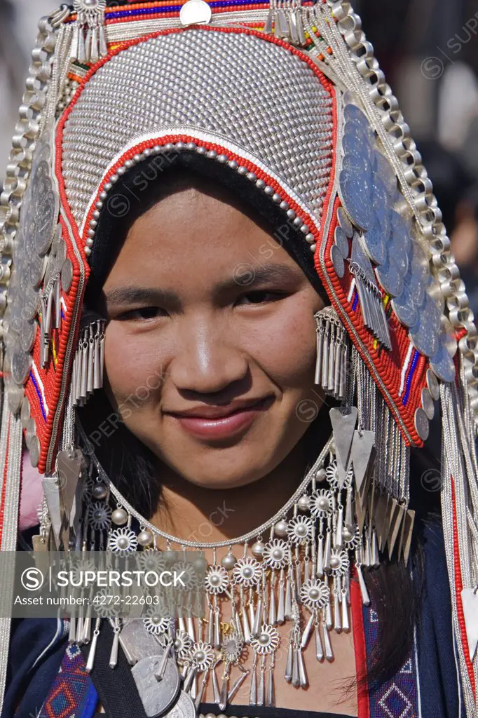 Myanmar, Burma, Kengtung. An Akha woman wearing traditional costume with a headdress of silver and glass beads.