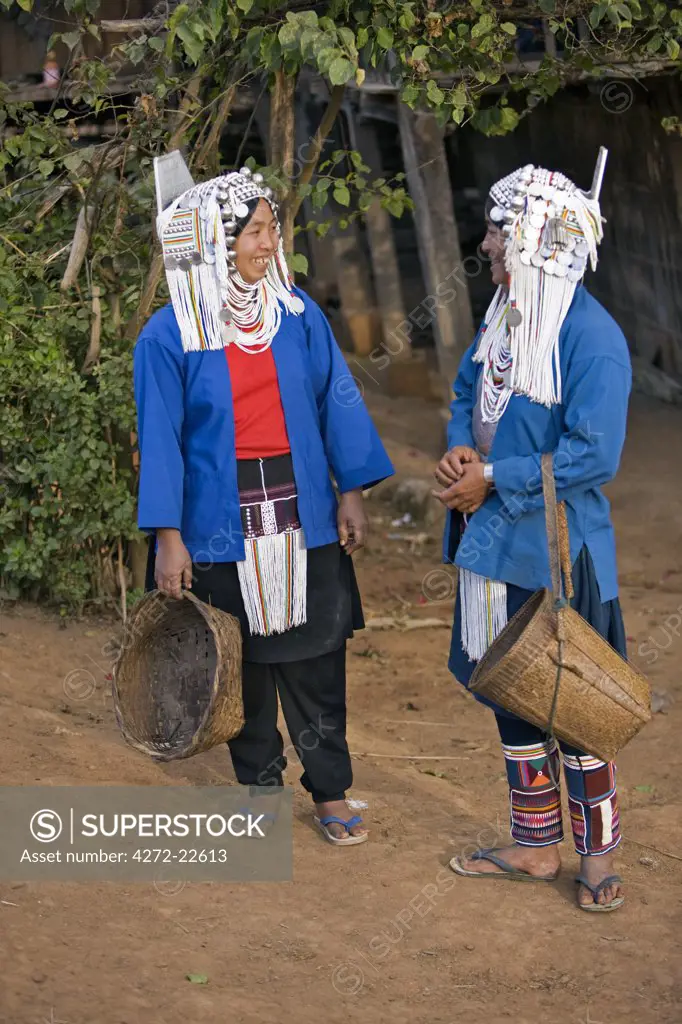 Myanmar, Burma, Namu-op. Two Akha women in all their finery pause to chat in Namu-op village.