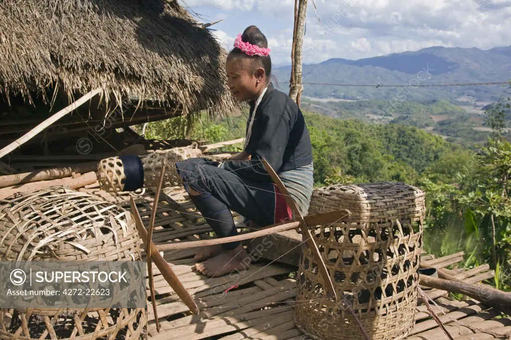 Myanmar, Burma, Pan-lo. A woman of the small Ann tribe spools cotton thread for weaving on the first floor bamboo platform of her home.