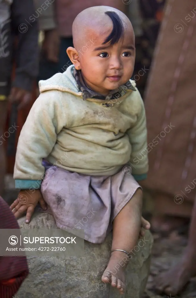 Myanmar, Burma, Rakhine State, Gyi Dawma. A young girl at Gyi Dawma village. The small tuft of hair on her shaven head is believed to protect her.