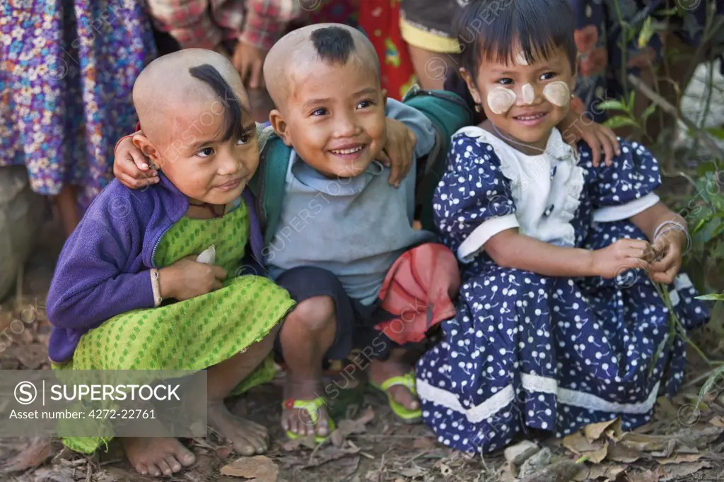 Myanmar, Burma, Rakhine State, Gyi Dawma. Three young friends at Gyi Dawma village. The small tufts of hair on the shaven heads of two of them are believed to protect them.
