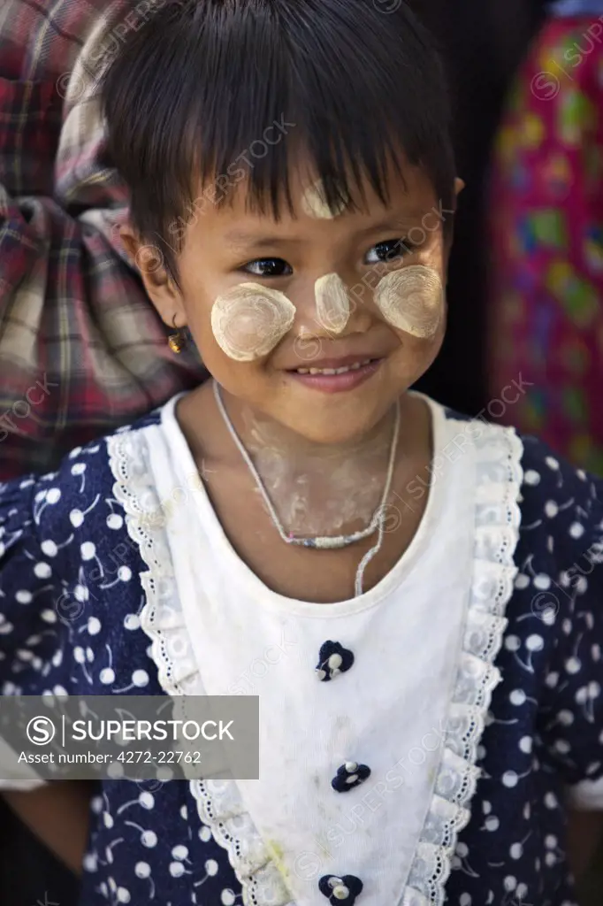 Myanmar, Burma, Rakhine State, Gyi Dawma. A young girl at Gyi Dawma village with her face decorated with Thanakha, a local sun cream and skin lotion.