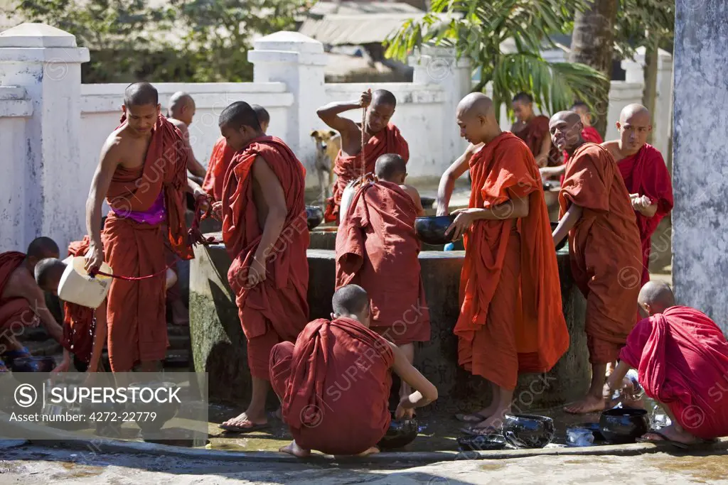 Myanmar, Burma, Rakhine State, Sittwe. Young novice monks wash their utensils at a well after their main meal at Pathain Monastery where 210 monks live.