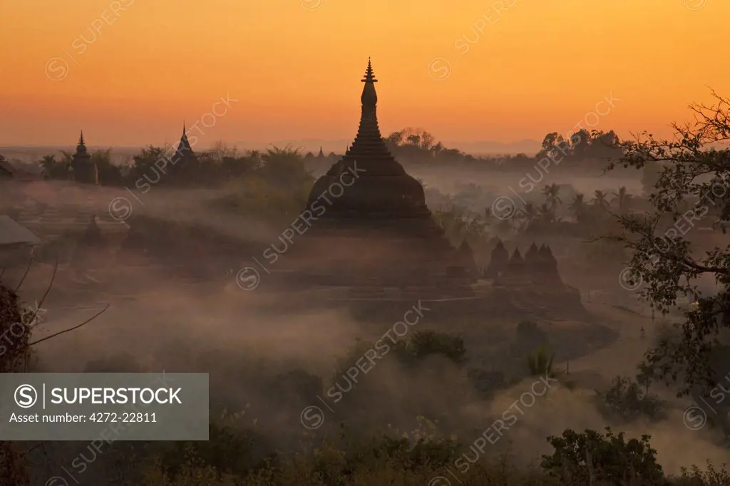 Myanmar, Burma, Mrauk U. Evening mist and smoke from village cooking fires swirl around Ratanabon Paya, Mrauk U, Rakhine State.