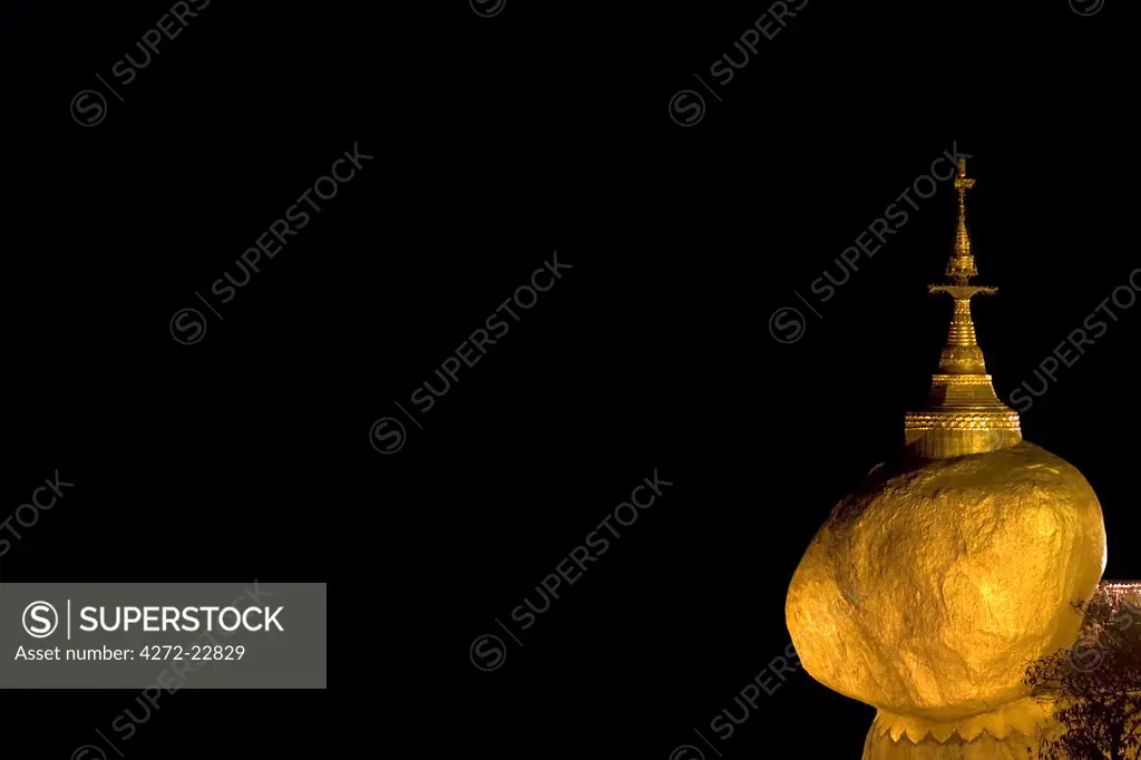 Myanmar, Burma, Golden Rock, Kyaiktiyo. The Golden Rock boulder, glowing at night, balanced precariously on the edge of Mount Kyaiktiyo.