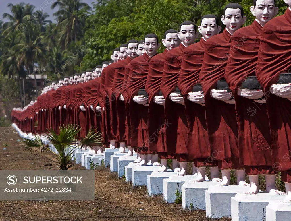 Myanmar, Burma, Pegu, Bago. A line of monk statues leading to Win Sein Taw Ya, the site of the world's largest reclining Buddha image, on the road between Pegu and Mudon.