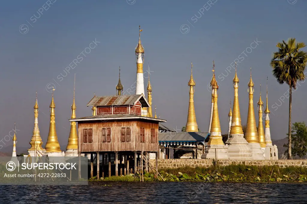 Myanmar, Burma, Lake Inle. A collection of golden stupas, with their 'htis' (umbrella tops) gleaming in the sun, in the middle of Inle Lake.