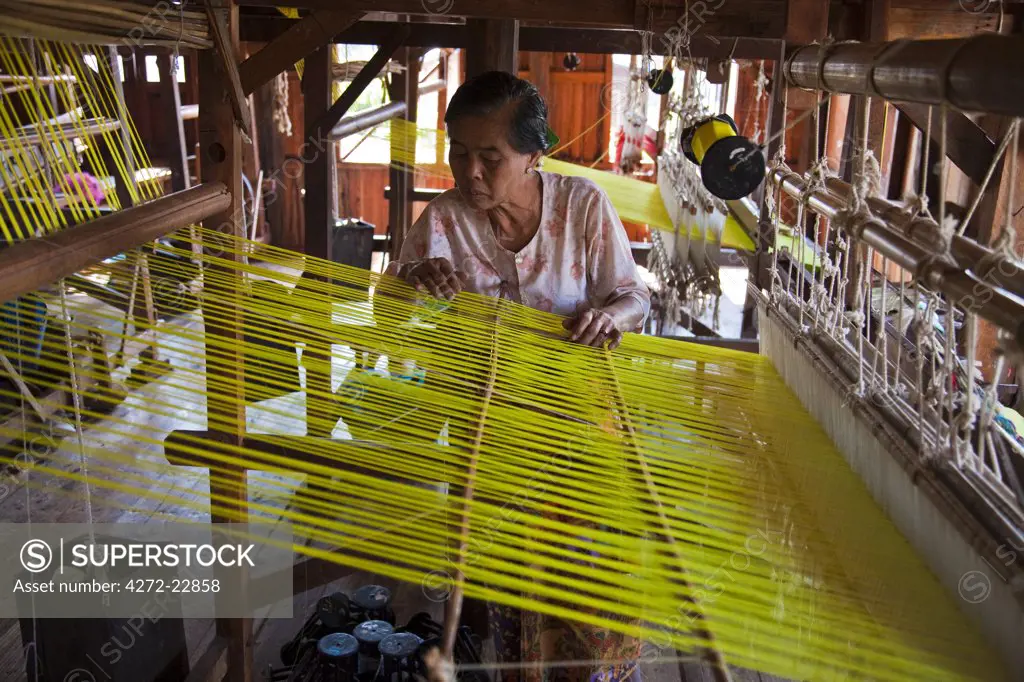 Myanmar, Burma, Inle Lake.  Checking the threads on a traditional loom in a weaving factory, Inle Lake, Myanmar