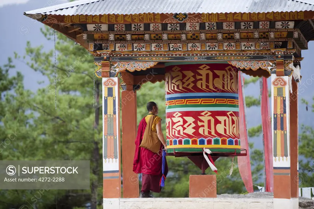 A monk and a prayer wheel on the path to the Paro Taktsang monastary in the Himalayan Kingdom of Bhutan