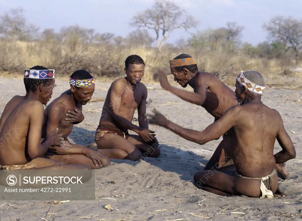 A group of Kung men enjoy a lively, competitive game in which the oldest generation of a hunting band pits its skills against a younger generation. The Kung live in the harsh environment of a vast expanse of flat sand and bush scrub country straddling the Namibia Botswana border.