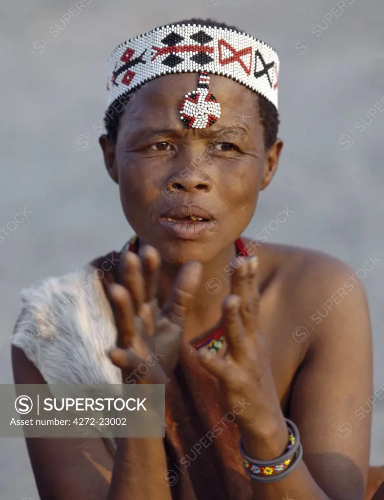 A Kung woman sings and claps her hands to the rhythm of her menfolk. The Kung are San hunter gatherers, often referred to as Bushmen. The Kung live in the harsh environment of a vast expanse of flat sand and bush scrub country straddling the Namibia Botswana border.