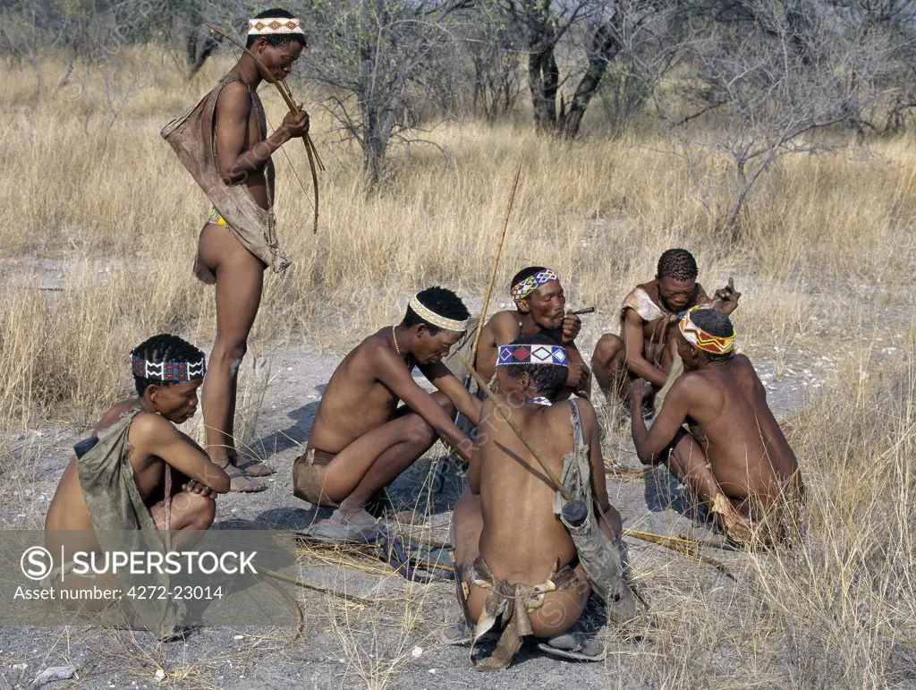 Kung hunter gatherers pause to smoke a communal metal pipe during a days hunting.The Kung live in the harsh environment of a vast expanse of flat sand and bush scrub country straddling the Namibia Botswana border.