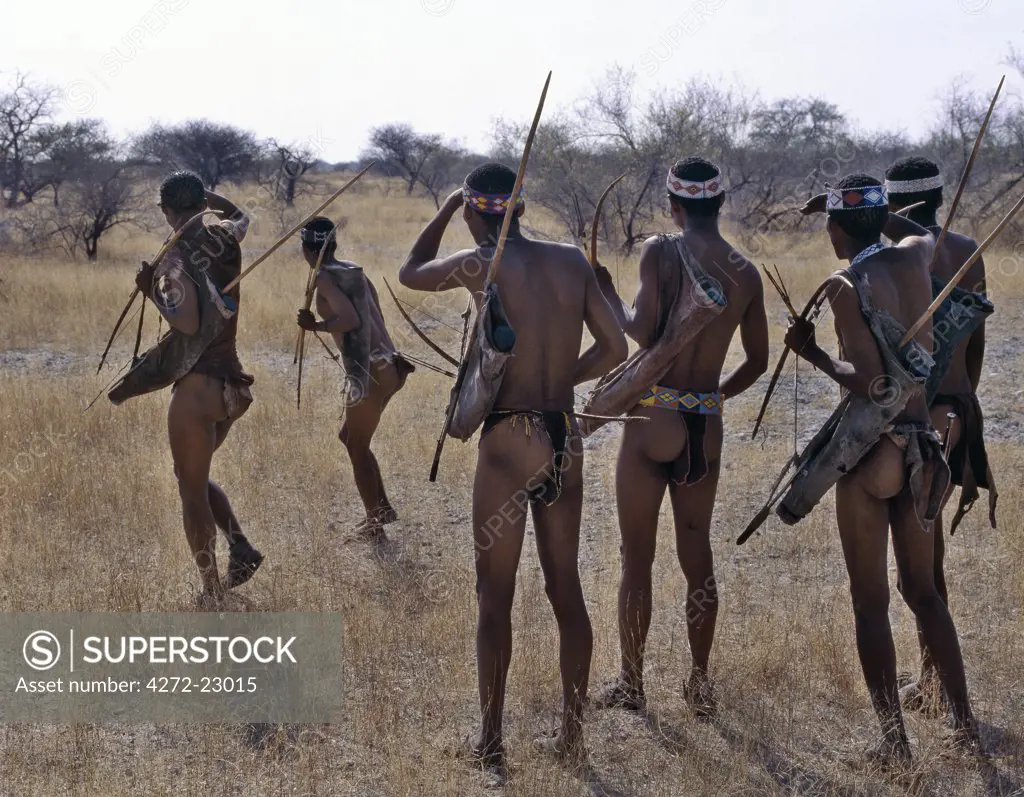 Kung hunter gatherers pause to smoke a communal metal pipe during a days hunting.The Kung live in the harsh environment of a vast expanse of flat sand and bush scrub country straddling the Namibia Botswana border.