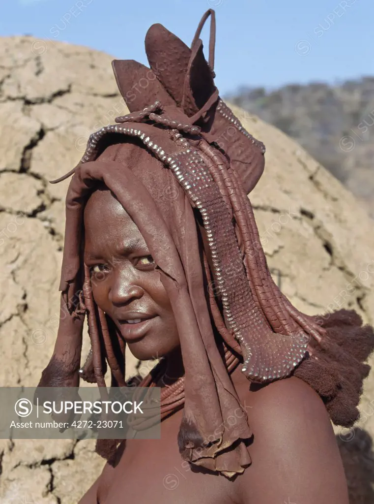 The bonnet like headdress of this young Himba girl is a visible sign of her recent marriage. Known as ekori, the leather garment is handed down from generation to generation and will be worn for at least a month after her wedding. The Himba are Herero speaking Bantu nomads who live in the harsh, dry but starkly beautiful landscape of remote northwest Namibia.