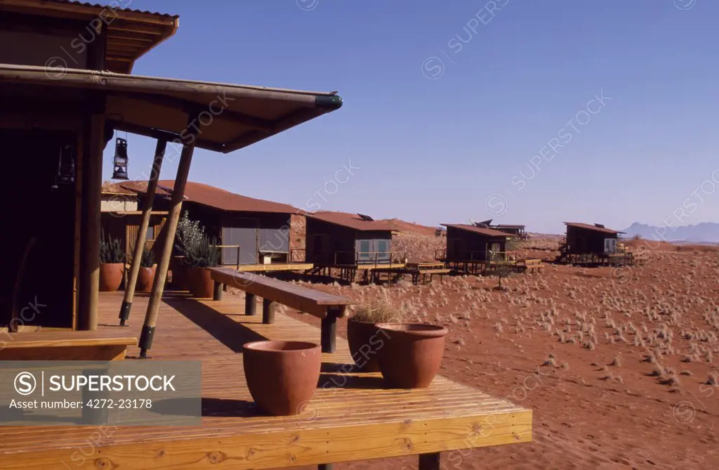 Red sands of the Namib Desert and verandahs of Dunes Lodge of Wolwedans Camp, Sossusvlei. Namibia.