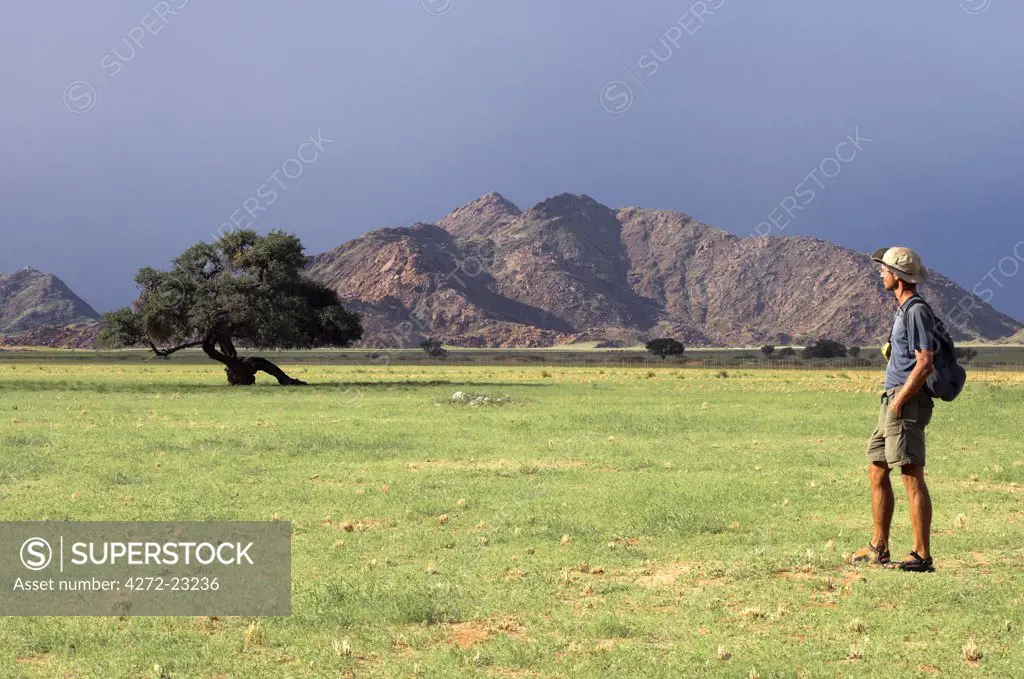 A tourist stands in front of the Naukluft mountains at Sesriem in the Namib-Naukluft National Park, Namibia.