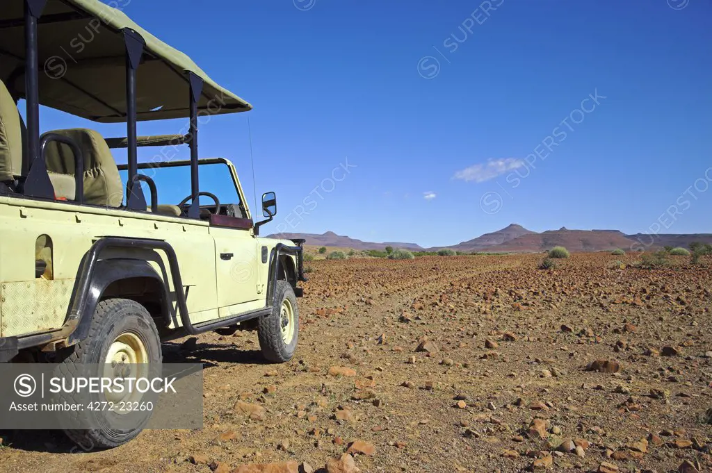 An open sided Land Rover on an offroad trail while tracking Black Rhino in the Palmweg concession in Damaraland, Namibia.