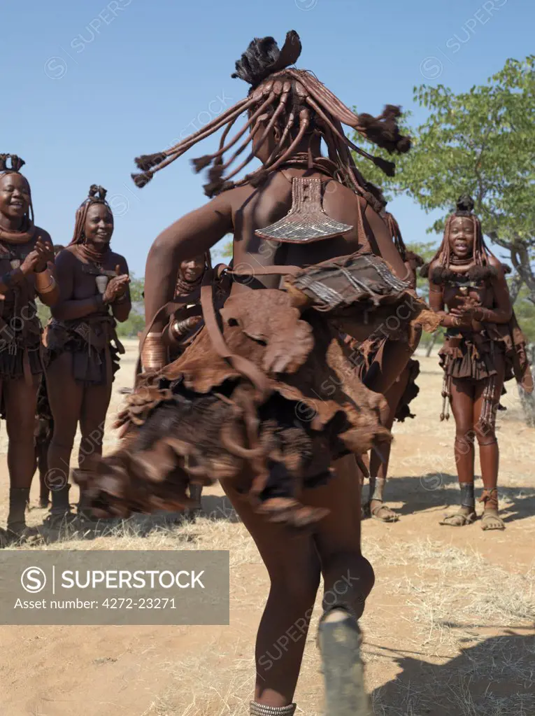 Himba women perform the otjiunda dance, stamping their feet, clapping and chanting while one of them gyrates in the centre of the circle. The Himba are Herero speaking Bantu nomads who live in the harsh, dry but starkly beautiful landscape of remote northwest Namibia.