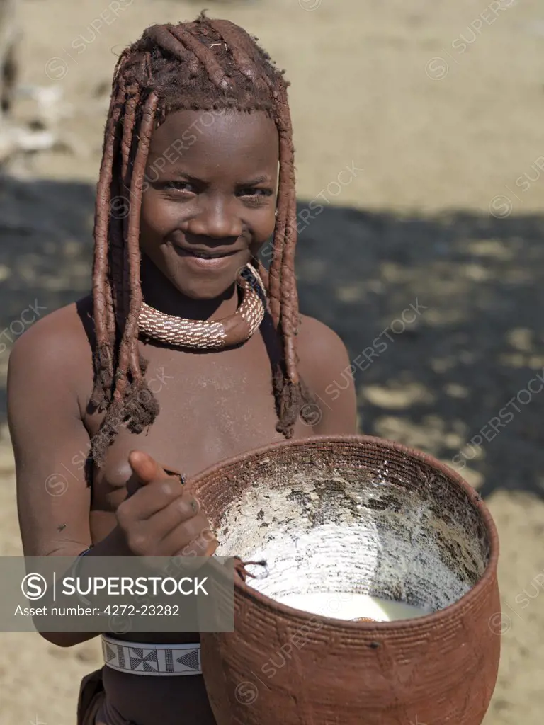A Himba girl carries home milk in a beautifully made woven container made from local grasses, which is plastered with animal fat and ochre on the outside to prevent it leaking.The Himba are Herero speaking Bantu nomads who live in the harsh, dry but starkly beautiful landscape of remote northwest Namibia.