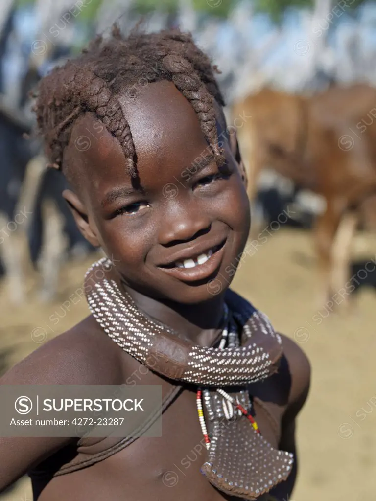 A young girl, her body lightly smeared with a mixture of red ochre, butterfat and herbs, wears a round white beaded necklace, called ombwari, a tradition of all Himba people. The Himba are Herero speaking Bantu nomads who live in the harsh, dry but starkly beautiful landscape of remote northwest Namibia.