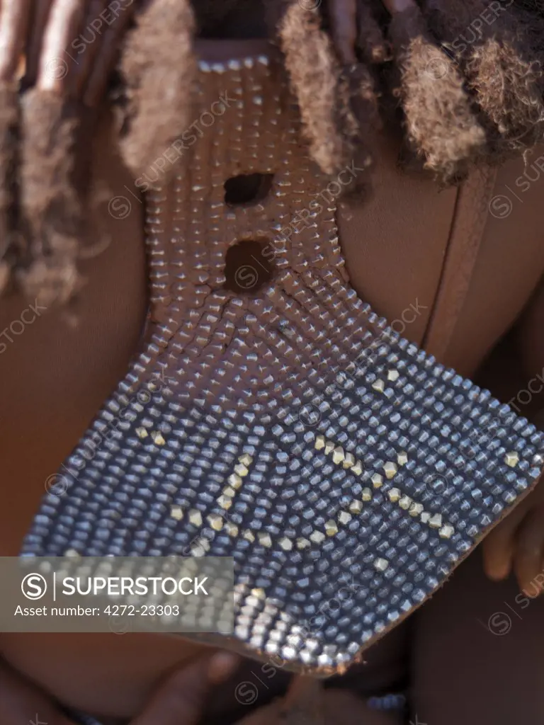 The traditional back ornament of Himba women, called eha. They are fashioned from homemade metal studs backed onto leather and come in a variety of patterns. The Himba are Herero speaking Bantu nomads who live in the harsh, dry but starkly beautiful landscape of remote northwest Namibia.