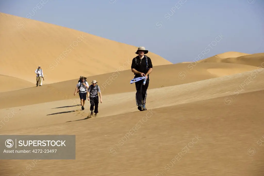 Namibia, Erongo Region, Swakopmund. A group of adventure racers cross the coastal dune belt near Swakopmund as they make their way towards the Namib Desert.