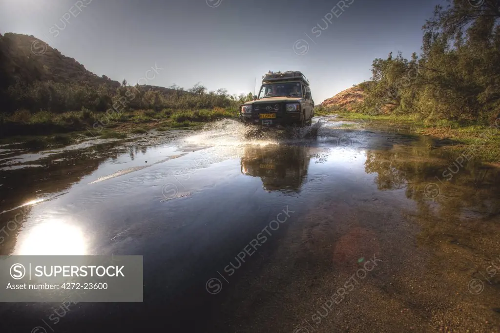 Namibia, Damaraland. Driving in a four wheel drive vehicle down the Ugab River near Brandberg Mountain in search of elusive Desert Elephants.