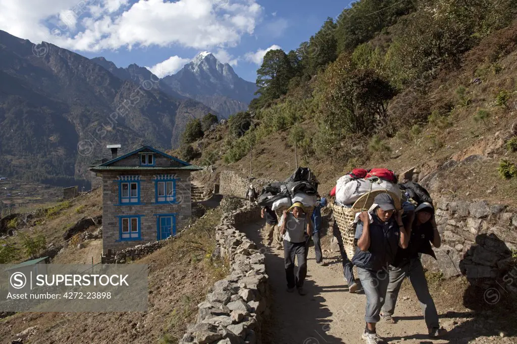Nepal, Everest Region, Lukla, Khumbu Valley. Porters on the Everest Base Camp trail looking down towards the Khumbu Valley