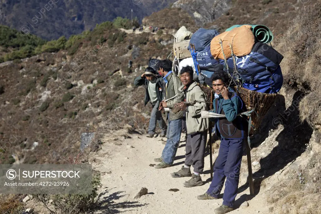 Nepal, Everest Region, Khumbu Valley. Porters on a trek in the Khumbu Valley resting on the side of the Everest Base Camp trail.