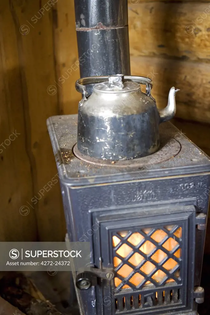 Norway, Troms, Lyngen Alps.  A traditional wooden cabin high in the mountains provides an 'open' source of accommadation where a wood burning stove heats a kettle of water.