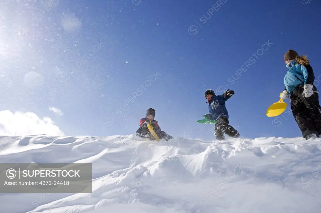 Norway, Tromso, Lyngen Alps. Young friends, wrapped up to protect them against the cold, enjoy playing in fresh snow fall in the Lyngen Alps. (MR)