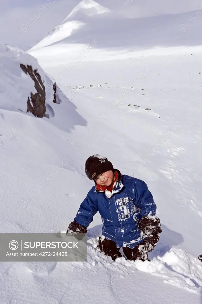 Norway, Tromso, Lyngen Alps. Young boy has extreme fun tobogganing in bright winter sun. (MR)
