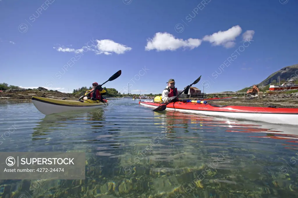 Norway, Nordland, Helgeland. Sea Kayaker explores the calm coastal waters of southern Nordland near the island of Rodoy (MR)