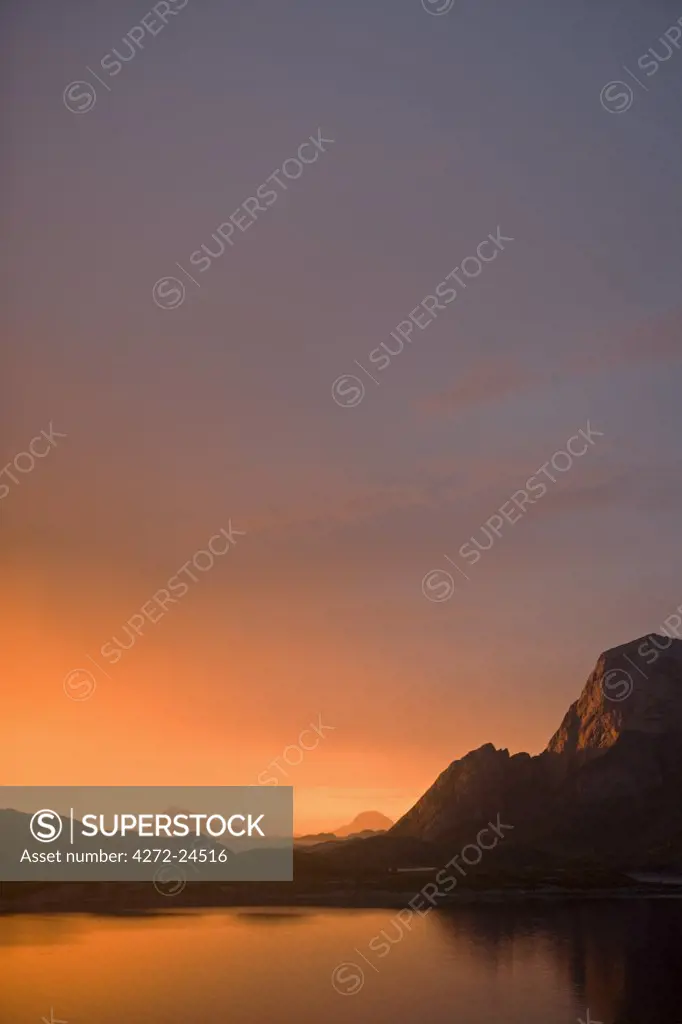 Norway, Nordland, Helgeland. The midnight sun over the islands surrounding the island of R__d__y Island dominated by the 400 metre high peak of R__d__yl__va, which translated means 'Lion of R__d__y' and which from a distance also looks like a sphinx