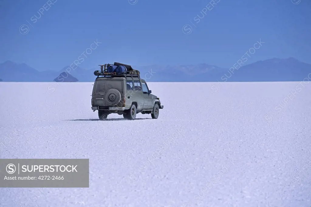 A vehicle drives across the crusted salt of the Salar de Uyuni, the largest salt flat in the world.