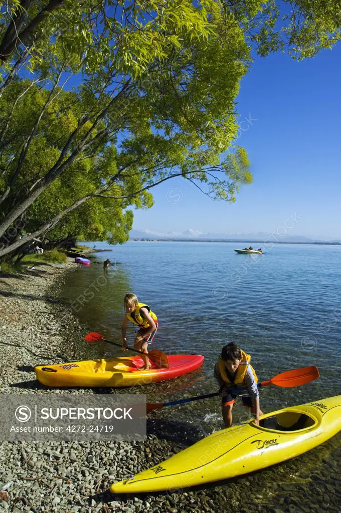 New Zealand, South Island, Mackenzie Country. Children Kayaking on Lake Benmore, Lake Benmore is a non-touristy camping area popular with domestic holidaymakers.