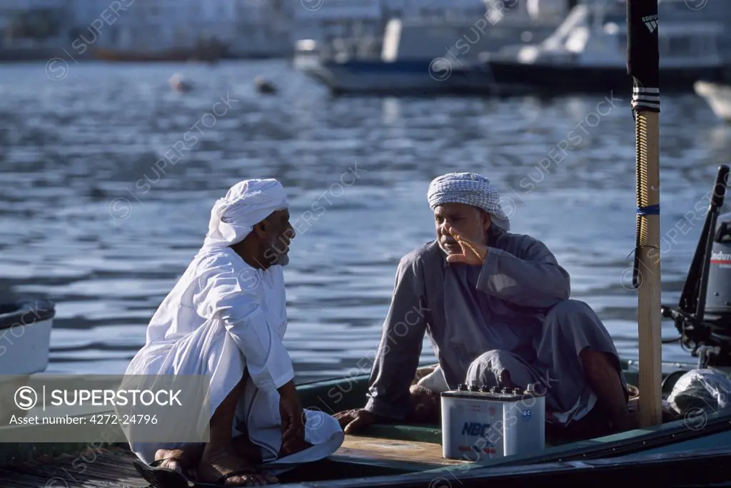 Fishermen sit chatting on their boat by the quay in front of Muttrah's fish souq