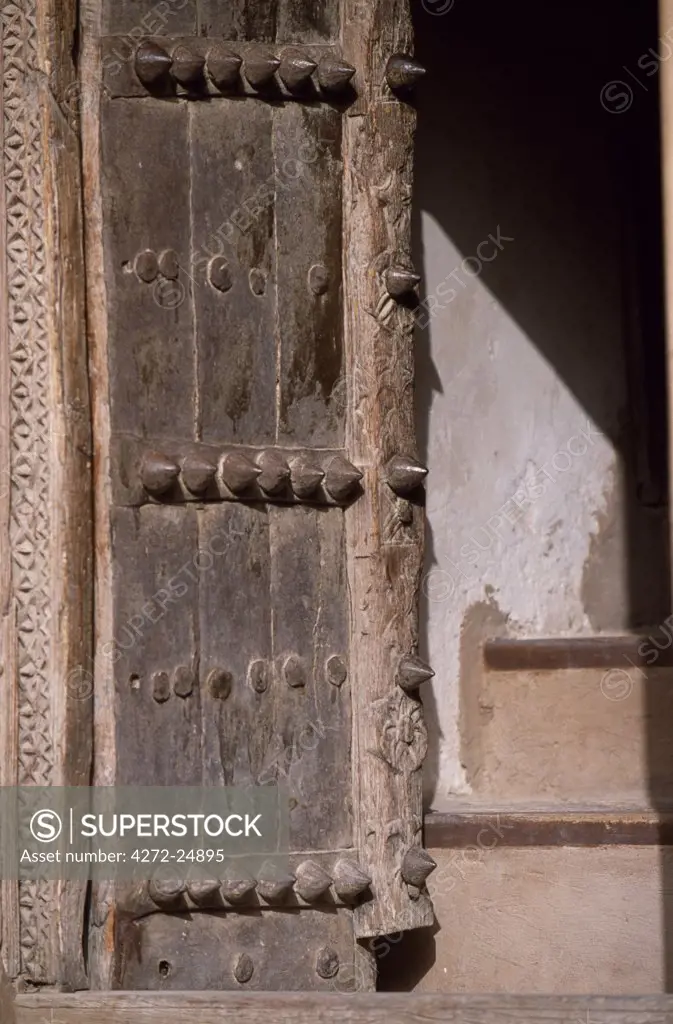 An old door with its carved surround and brass studs in Nizwa Fort, built in the 17th Century by Imam Sultan bin Saif bin Malik Al Ya'arubi.