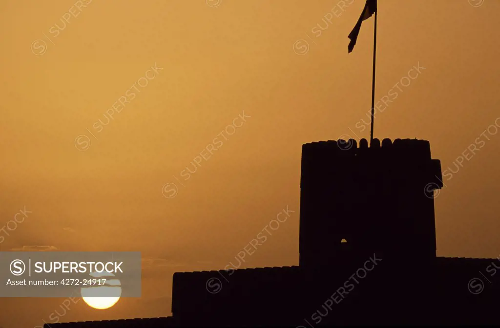 Silhouette of one of the towers of Ras al Hadd Castle at sunset. The 450 year old castle stands looking  out to sea.  It has 3 towers and a courtyard large enough to take all of the villagers when they were threatened with invasion.  An escape tunnel travels 200m outside the fort into what was then a dwelling.