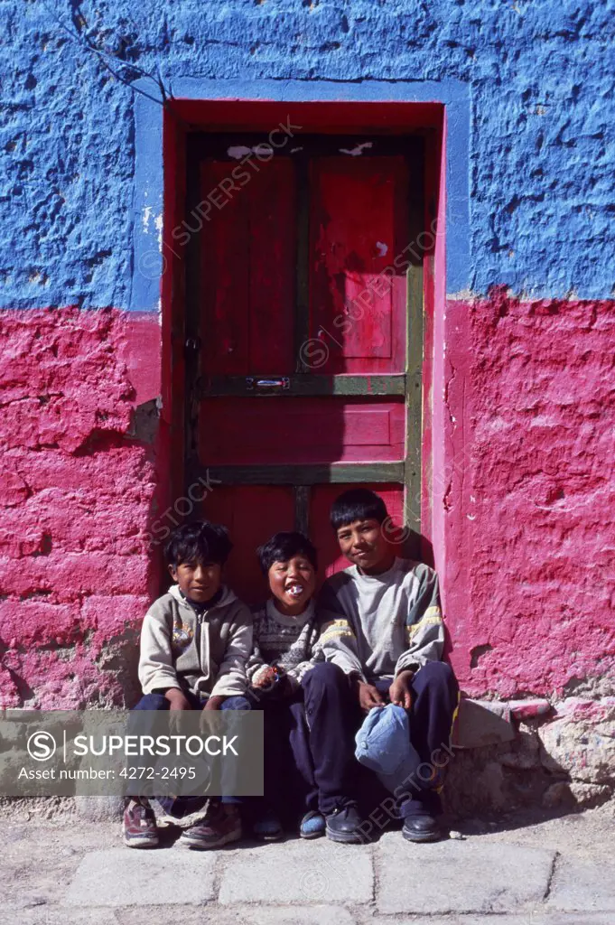 Three local boys sit in the doorway of a brightly painted  house in the village of Tahua on the northern shore of the Salar de Uyuni, the world's largest salt flat.
