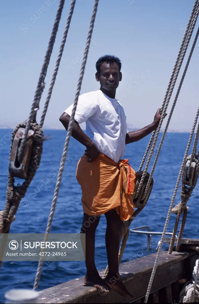 One of the crew members of S/Y Sanjeeda standing on the rail of the boat.  Sanjeeda is a traditional kotiya dhow of the type that traded  throughout the Indian Ocean