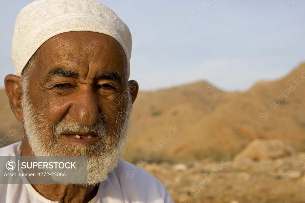 Oman, Muscat Region, Bandar Khayran. A old farmer sits down for a chat dressed in traditional Omani clothing.